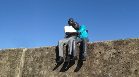 3D-printed refugees, (father-son pair from Rwanda) sit on a wall in Amsterdam.