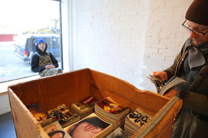 ryan Leitgeb looks through a crate of Larry Clark snapshots at the Home Alone 2 gallery under the eye of Leo Fitzpatrick, left, the gallery's co-owner. Nicole Bengiveno/The New York Times