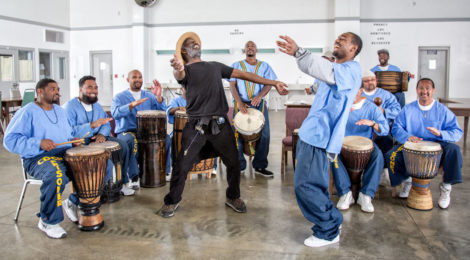 Peter Merts, Instructor Wilfred Mark of Dance Kaiso, in black, during drum and dance class at Salinas Valley State Prison, 2015, archival pigment print, 16 x 20 inches.